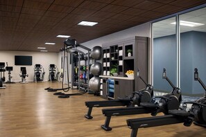 A gym with exercise equipment, a wall-mounted TV, and a counter with towels and plants. - Sheraton Denver Downtown Hotel (Denver)