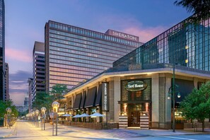 A modern hotel with a 'Sheraton' sign, a 'Yard House' restaurant, and outdoor seating with umbrellas. - Sheraton Denver Downtown Hotel (Denver)