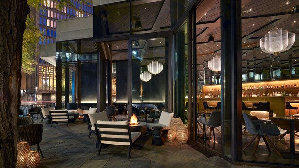 An outdoor seating area with modern furniture, a fire feature, and a bar with shelves of bottles.