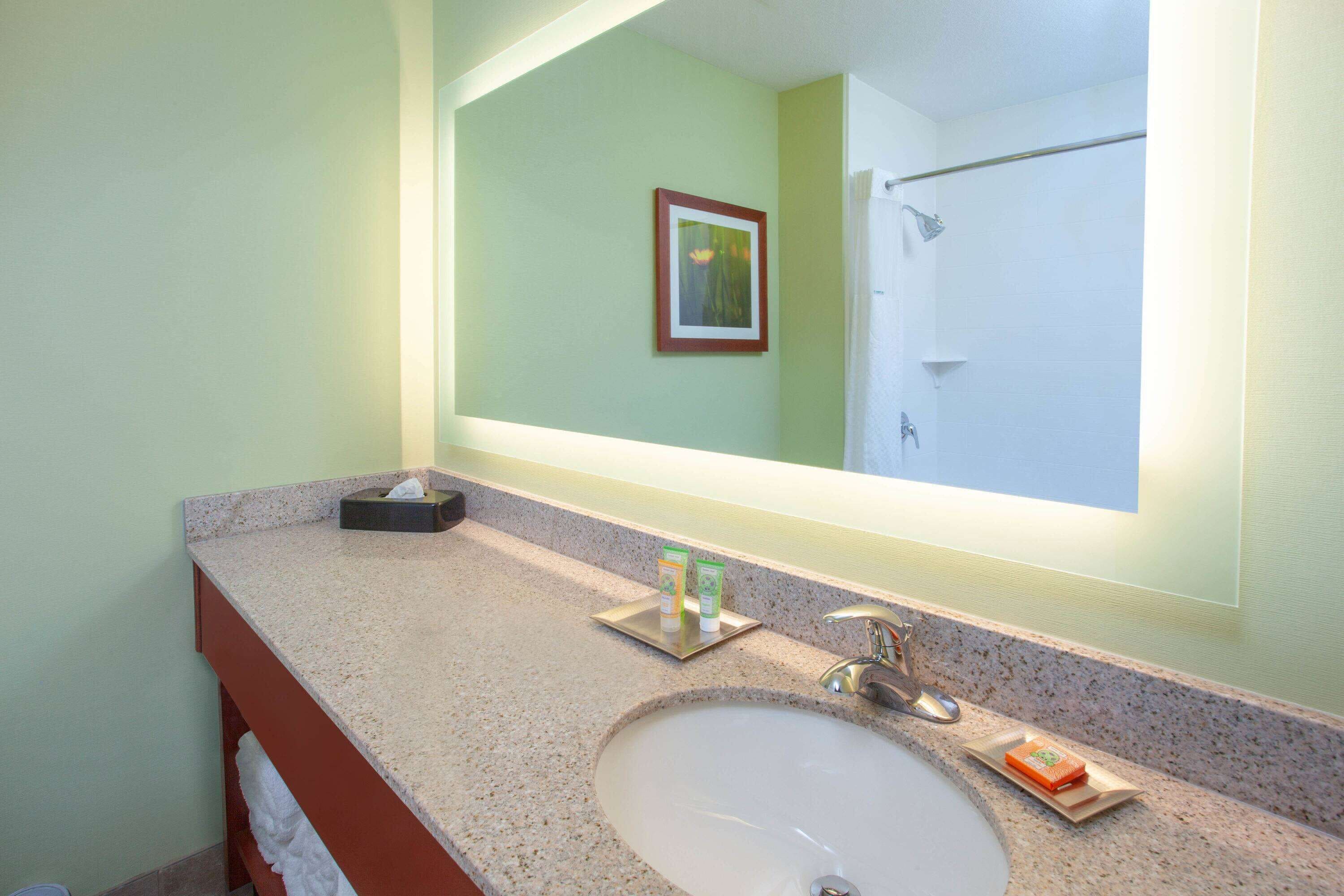Un baño con lavamanos, espejo y toallero.