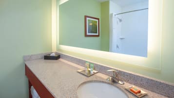 Un baño con lavamanos, espejo y toallero.