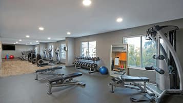 A gym with various exercise equipment, a large window, and a mirror.