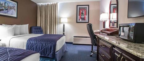 Habitación de hotel con dos camas, un escritorio con microondas, una silla, una lámpara de escritorio y un espejo grande.
