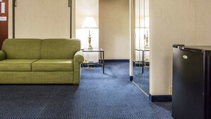 Ein Hotelzimmer mit einem grünen Sofa, einem kleinen Tisch mit einer Lampe und einem Kühlschrank.