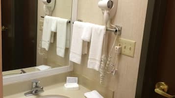 A bathroom with a sink, two hair dryers mounted on the wall, and a mirror.