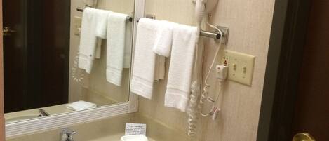 A bathroom with a sink, two hair dryers mounted on the wall, and a mirror.