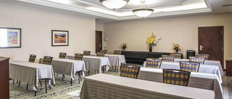 A conference room with tables and chairs, a fireplace, and framed artwork on the walls.