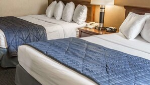 Ein Hotelzimmer mit zwei Betten, jeweils mit einer anderen Bettdecke, einem Nachttisch mit Lampe und einem gerahmten Bild an der Wand.