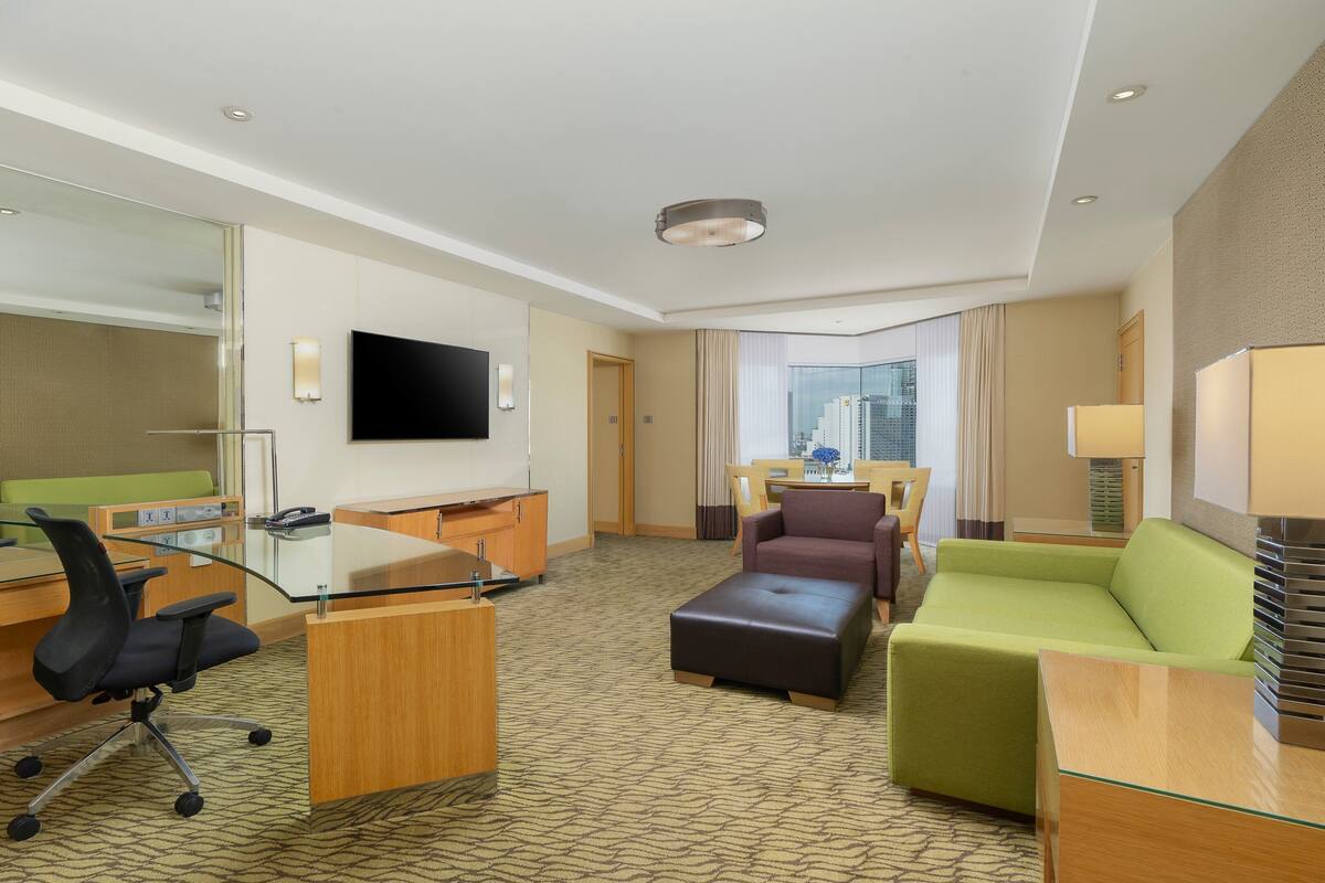 Una habitación de hotel con escritorio, silla de oficina, sofá y televisor.