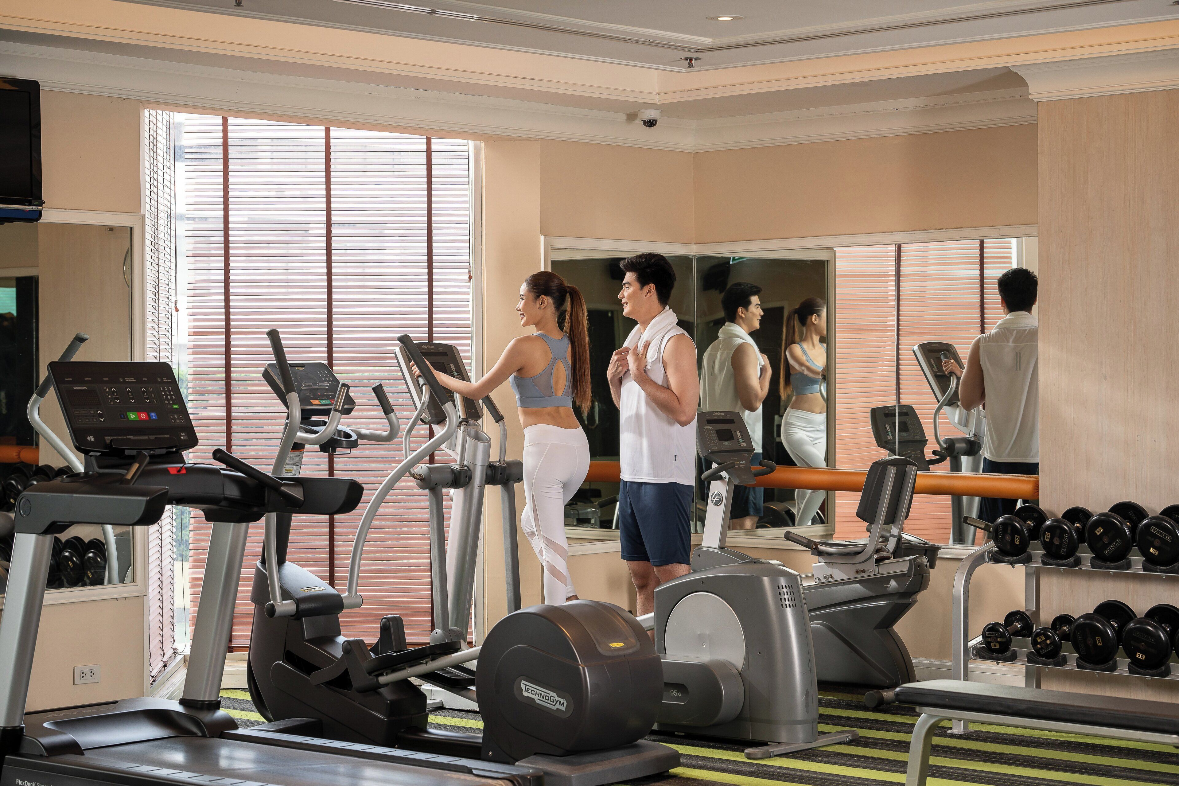A gym with treadmills, elliptical machines, and weight stations.
