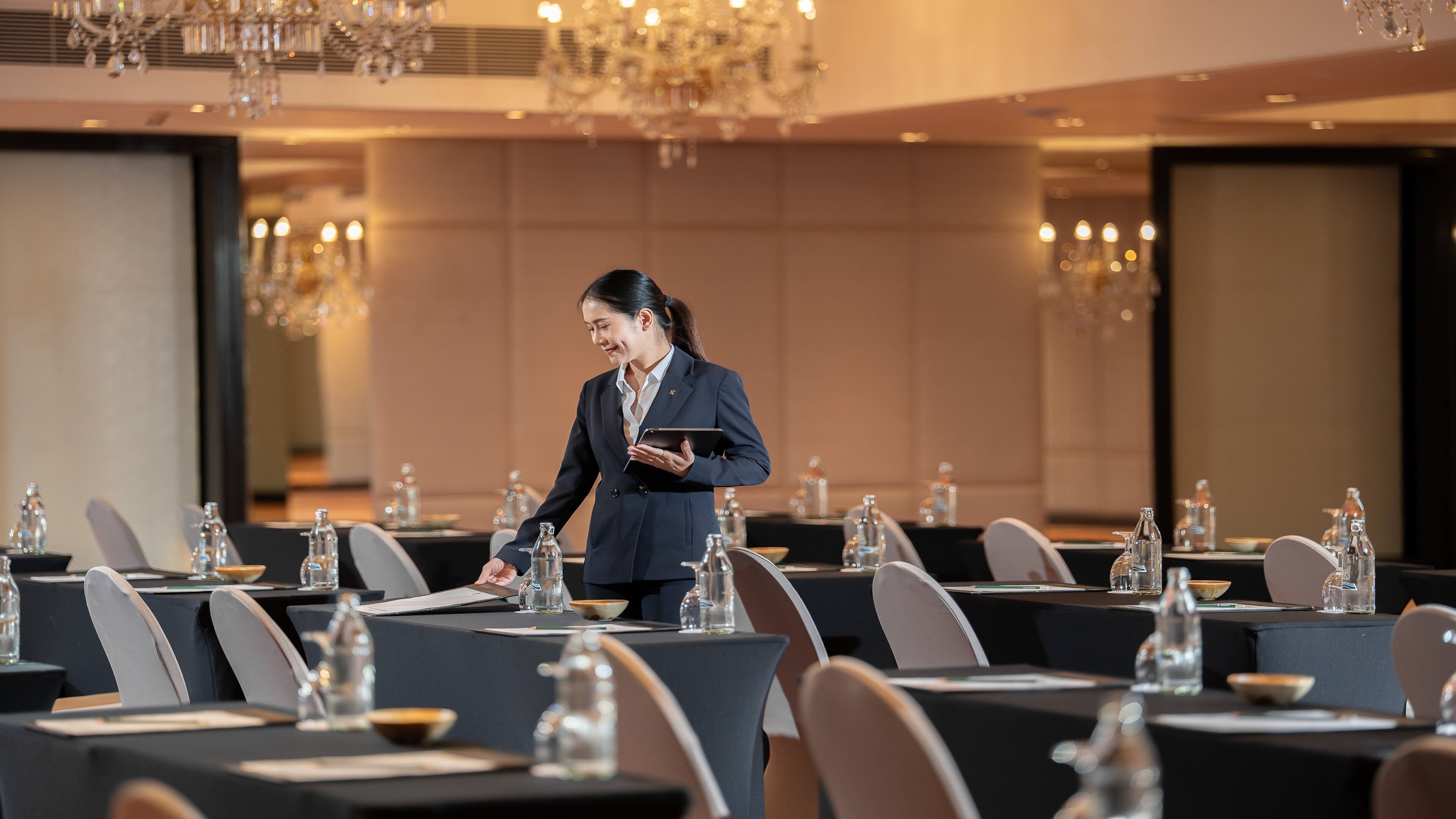 A conference room with tables set for a meeting, equipped with water bottles and notepads.