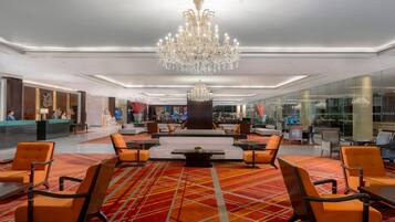 A spacious lobby with a large chandelier, seating area, and a reception desk.