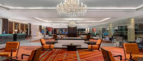A spacious lobby with a large chandelier, seating area, and a reception desk.