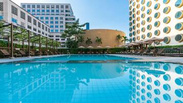 Una piscina al aire libre, sombrillas, sillones reclinables de piscina