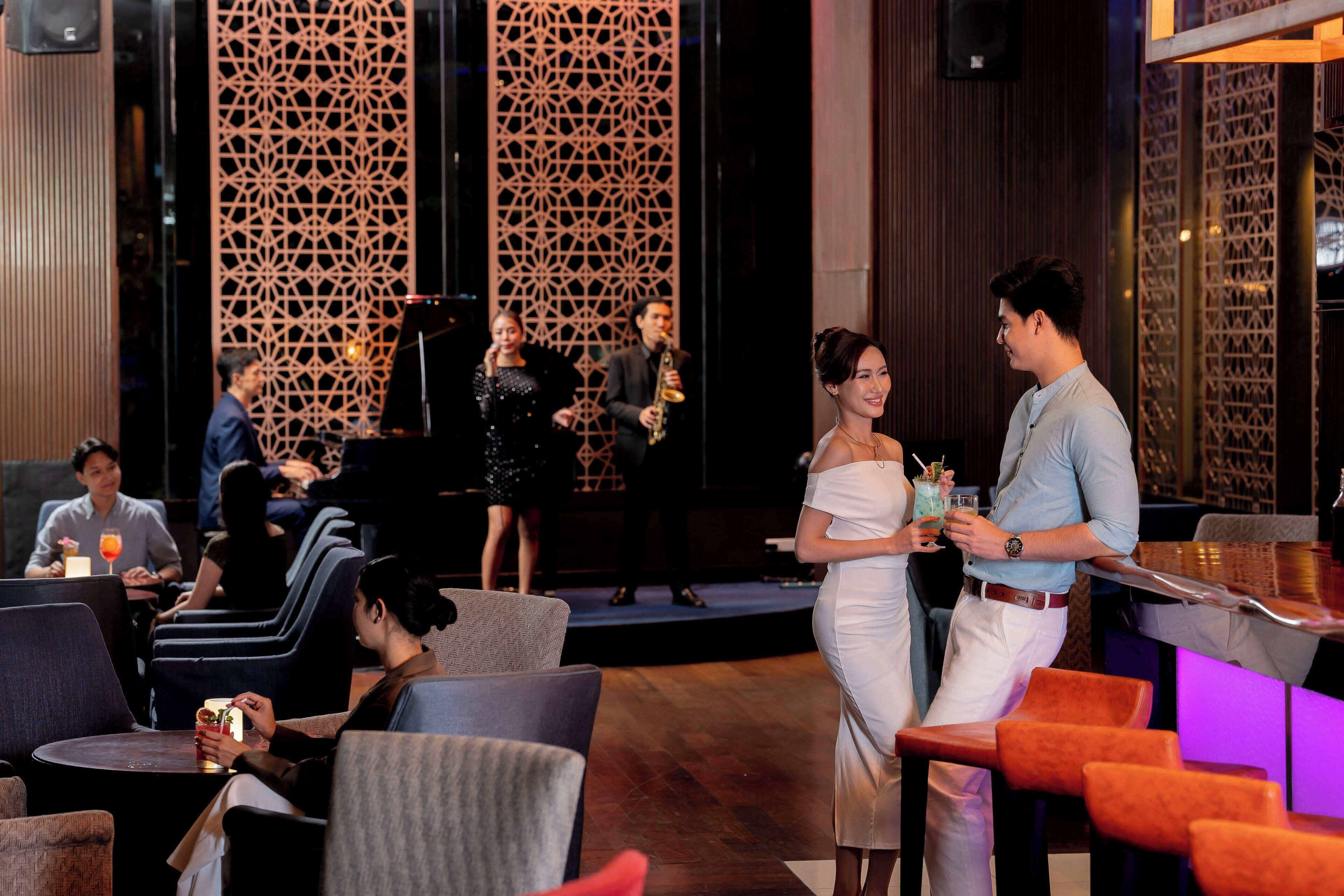 A modern indoor setting with a stage, seating areas, and a bar.