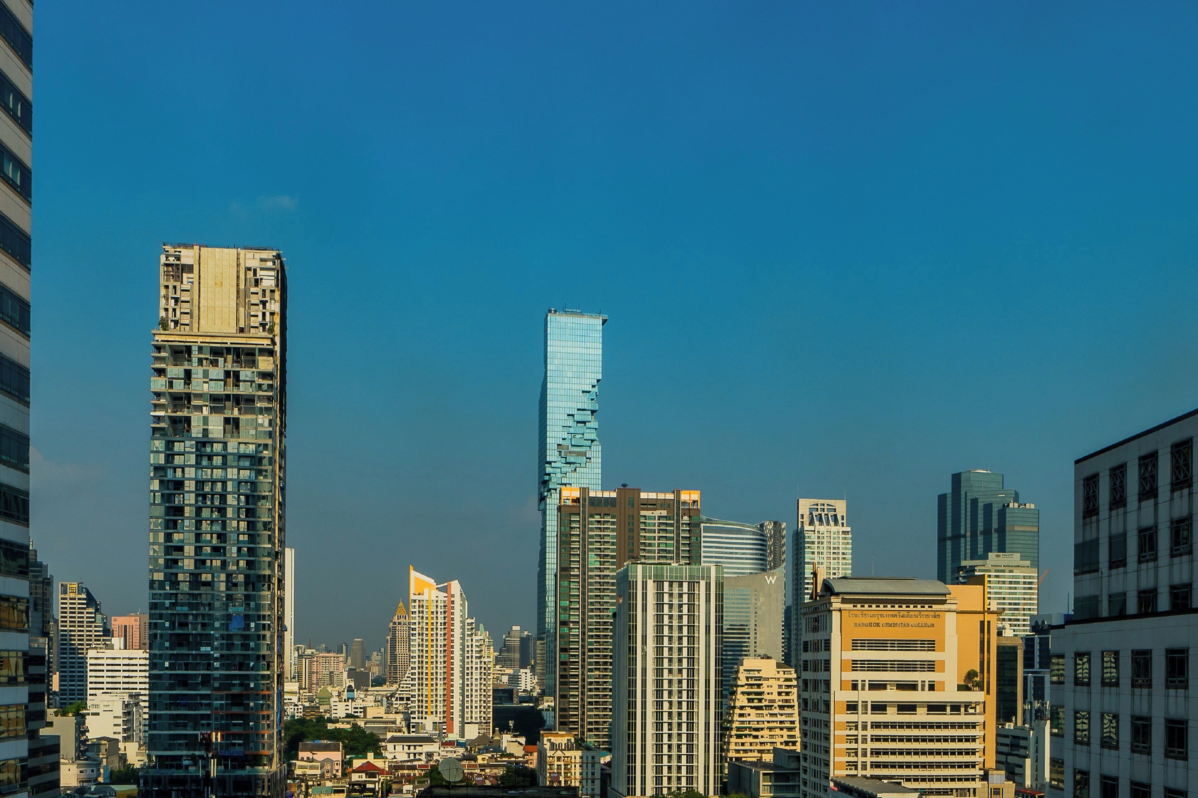 A cityscape with modern high-rise buildings, including a prominent skyscraper with a unique design.