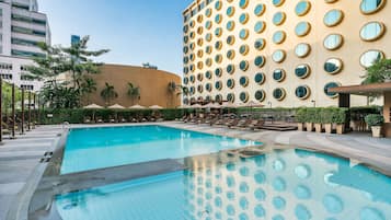 Una piscina al aire libre, sombrillas, sillones reclinables de piscina