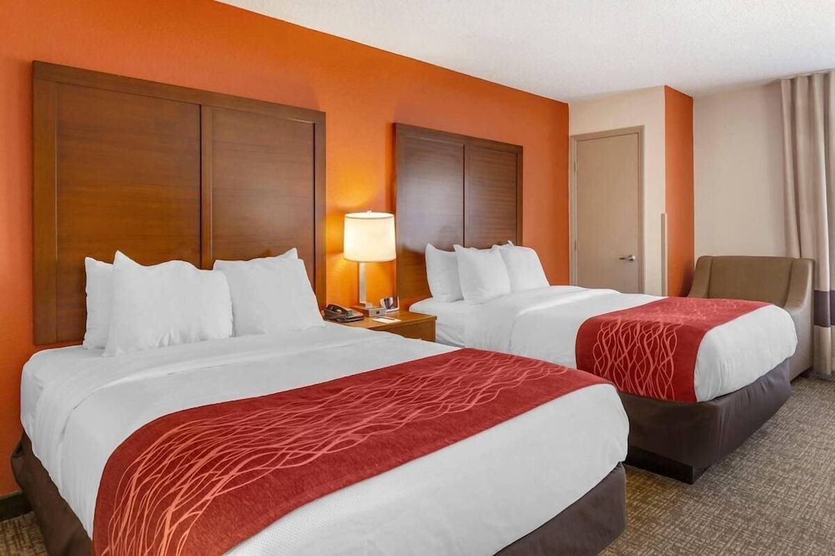 Une chambre d’hôtel avec deux lits, une table de chevet, une lampe et une chaise.