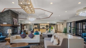 Una moderna hall d'hotel con camino, divani, area ristoro e reception.