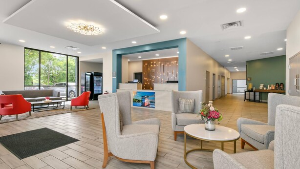 Un hall espacioso con muebles modernos, una recepción y grandes ventanales que ofrecen vistas al exterior.