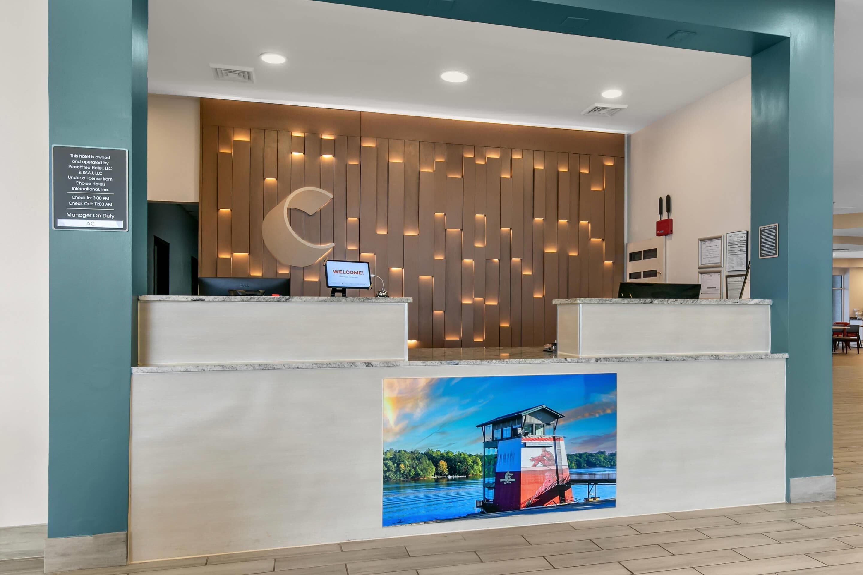 Un mostrador de recepción de hotel con diseño moderno, una computadora y un cartel de bienvenida.