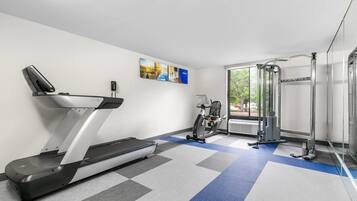 A gym with a treadmill, stationary bike, and weight machines.