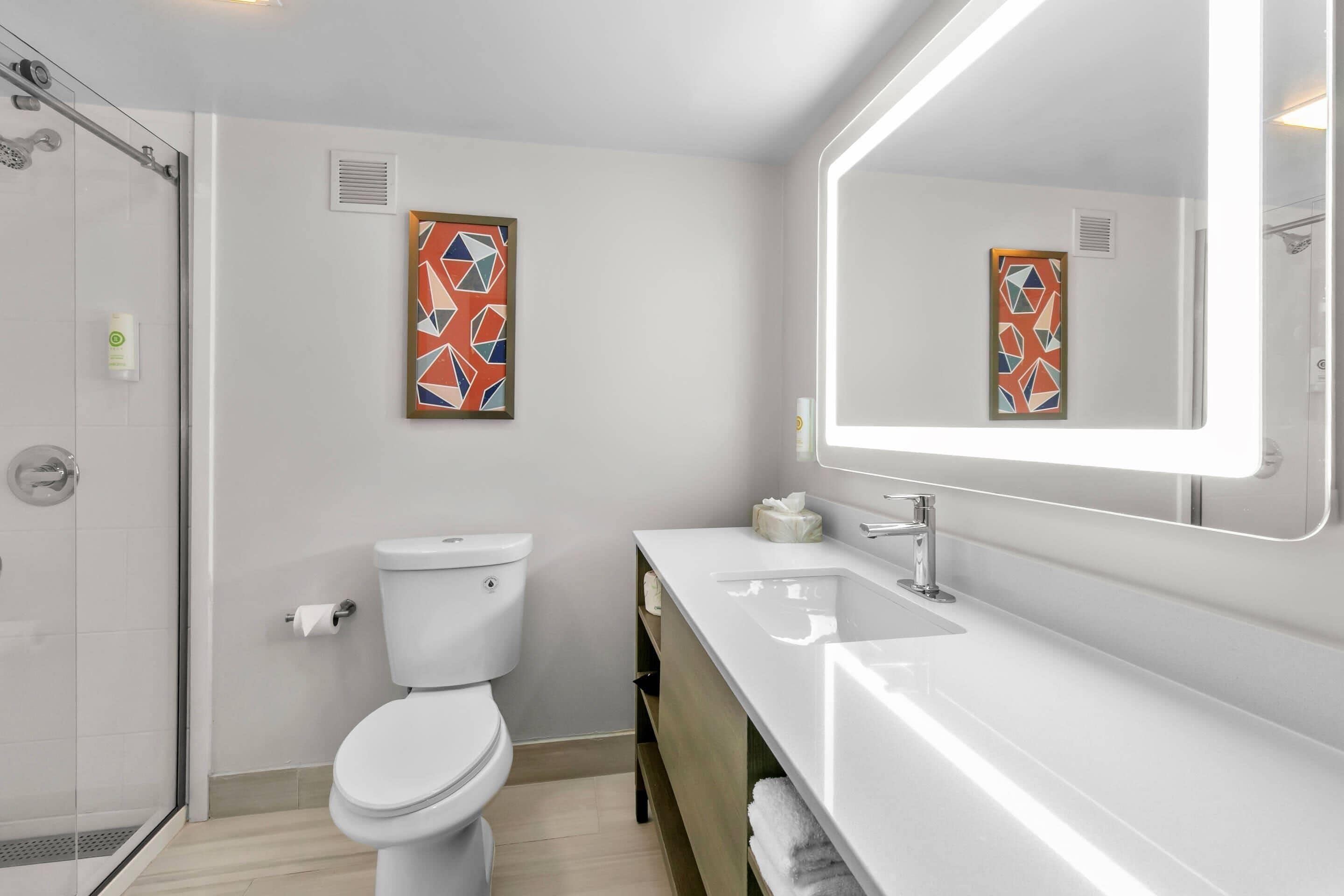 A modern bathroom with a toilet, shower, and sink.