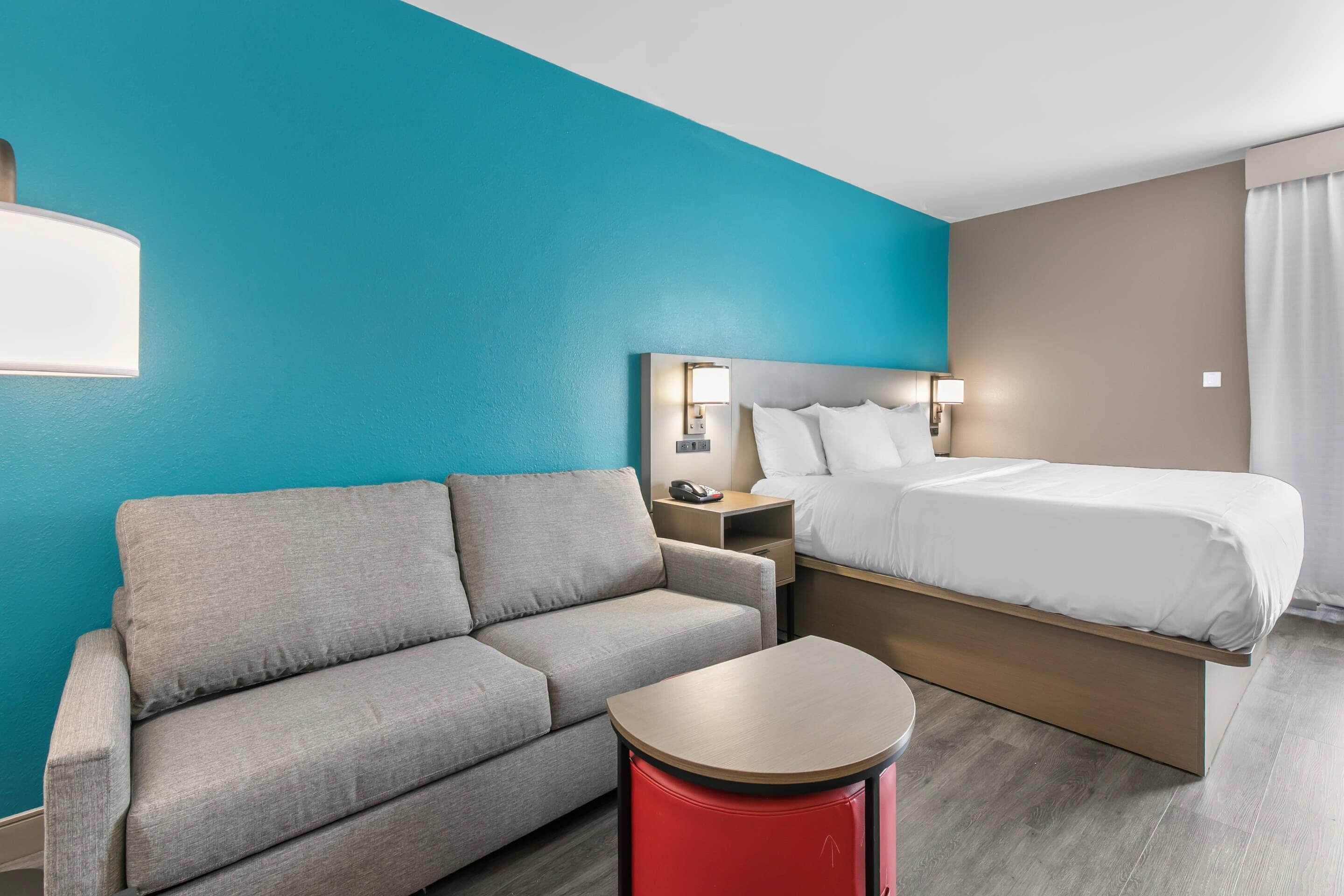 Et hotelværelse med seng, sofa, lille bord og natbord.