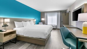 Habitación de hotel con cama, escritorio, silla y televisor.