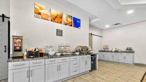 Cocina moderna con armarios blancos, una cafetera y una vitrina con alimentos.