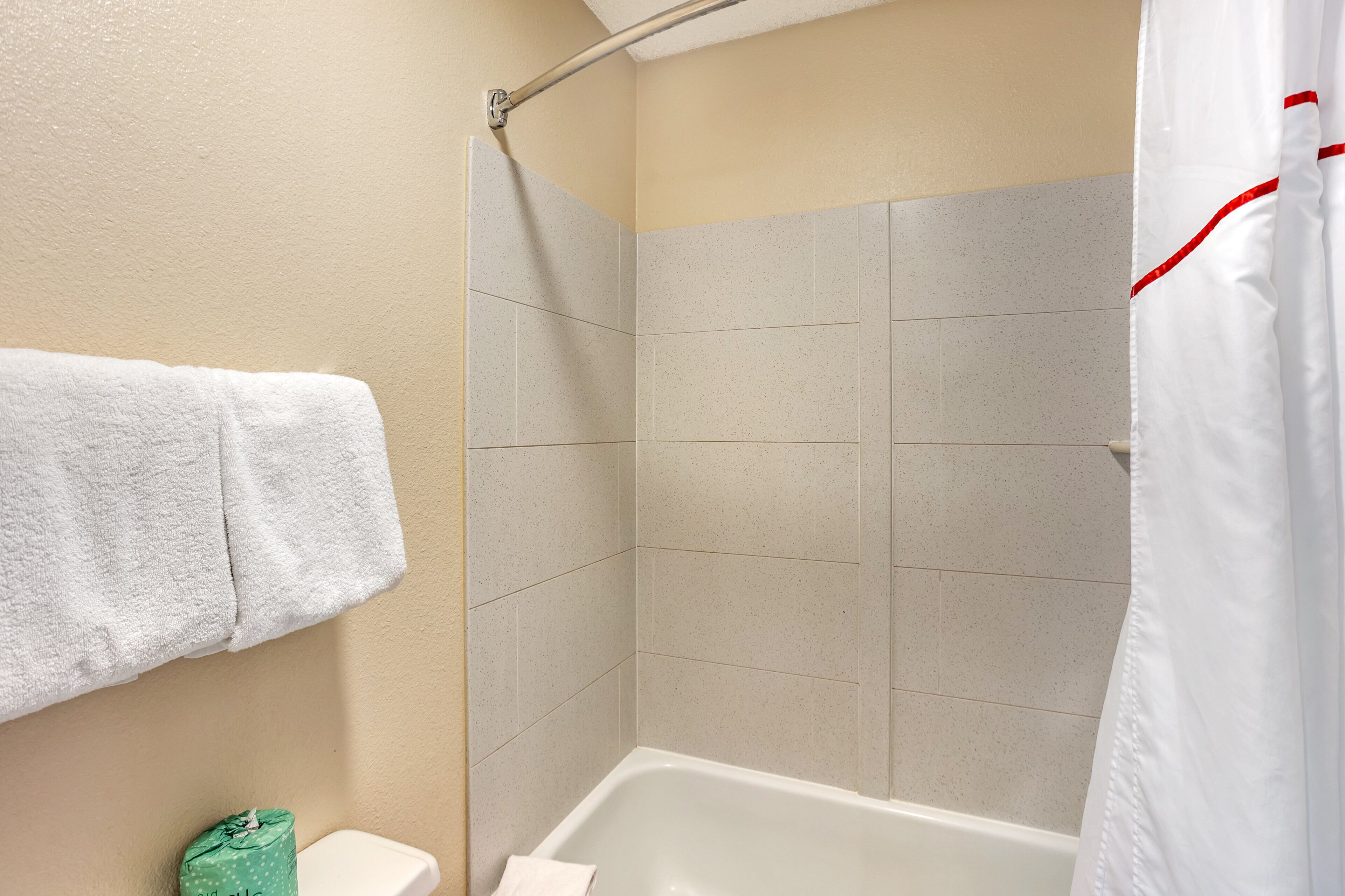 Un baño con bañera, cortina de ducha y una toalla colgada en la pared.