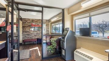 A Red Roof Inn with a stone wall, a bench, an ATM, and a view of the outside.