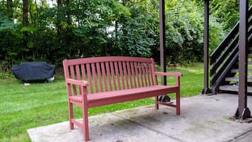 A red bench on a concrete slab in a grassy area with trees in the background.