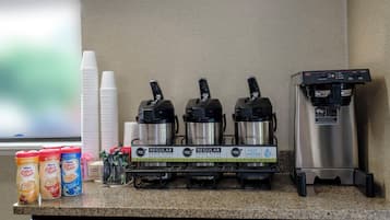 A coffee station with three Bunn coffee makers, a water dispenser, and various coffee pods and creamer options.