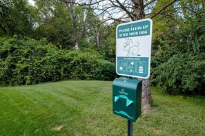 A sign instructing to clean up after your dog and dispose of waste, with a Poopy Pouch dispenser. - Red Roof Inn Danville, PA (Danville)