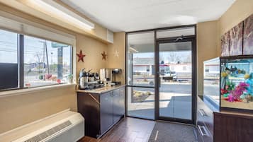 A commercial kitchen with a coffee machine, a large window, and a view of the parking lot.