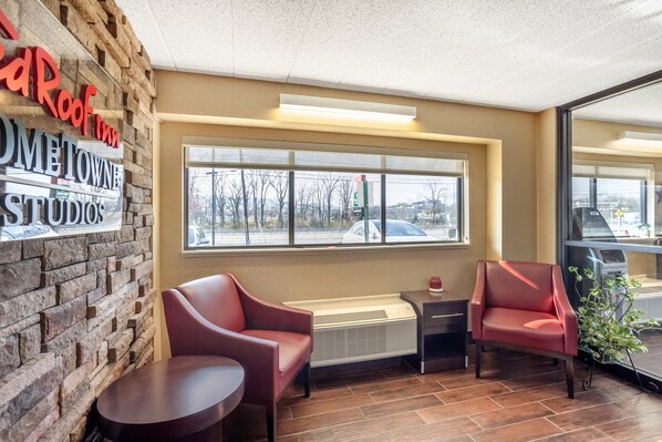 A cozy interior with brick walls, a large window, and two red chairs.