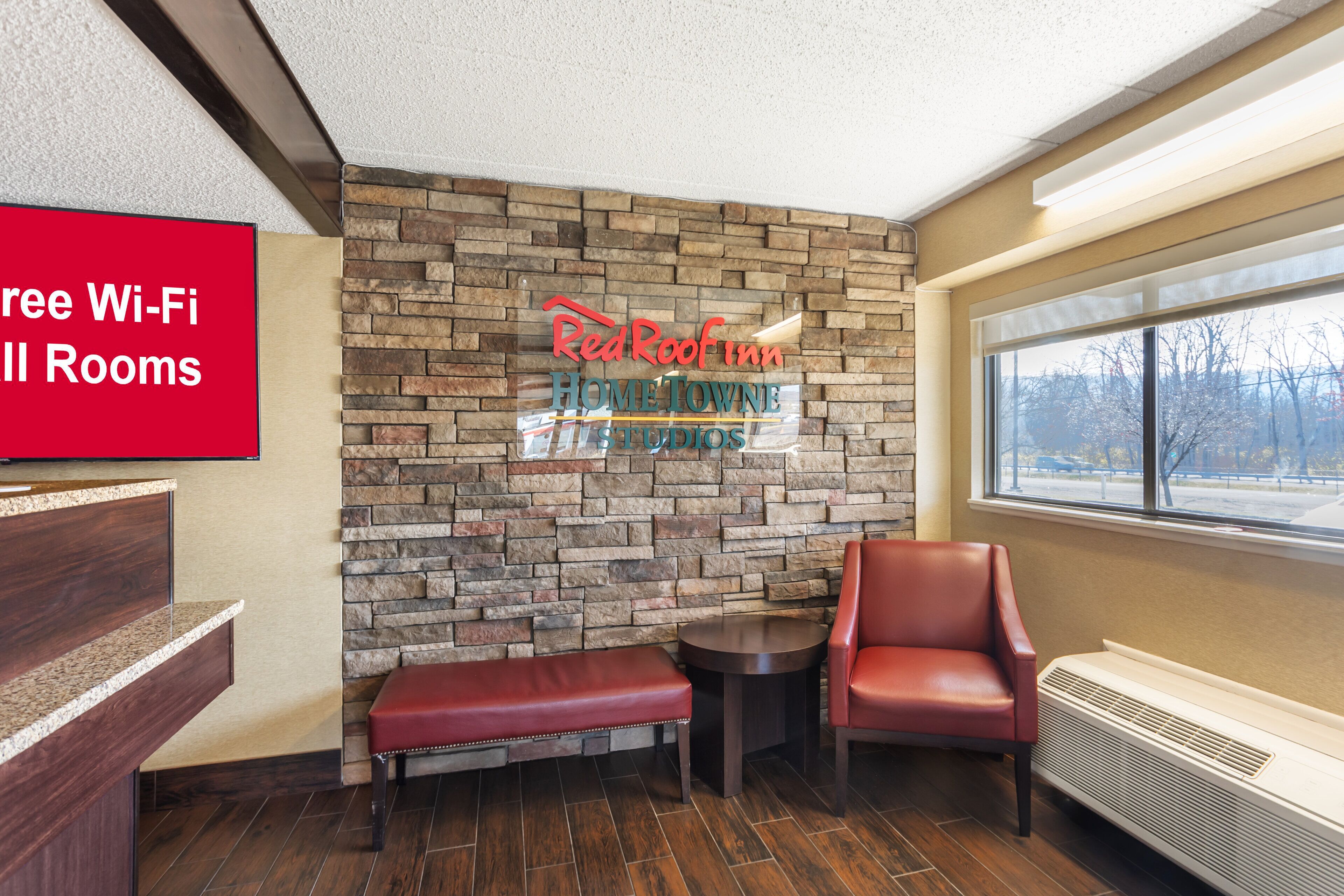 Een receptiezone van Red Roof Inn met een stenen muur, een bank, een stoel en een raam met uitzicht.