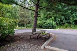 A park with a picnic table and benches, surrounded by trees and a road. - Red Roof Inn Danville, PA (Danville)