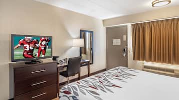 Ein Hotelzimmer mit einem Bett, einem Schreibtisch, einem Fernseher und einer Tür.