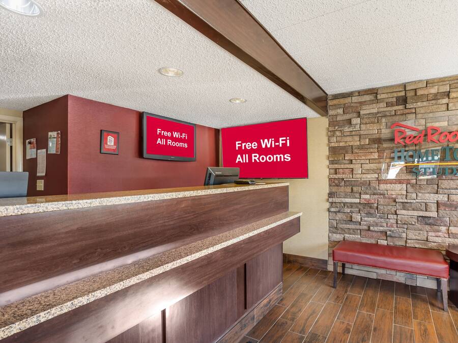 Zona de recepción de un hotel con mostrador, una banca y una pared de fachada de piedra.