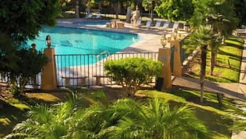 Una piscina al aire libre, sombrillas, sillones reclinables de piscina