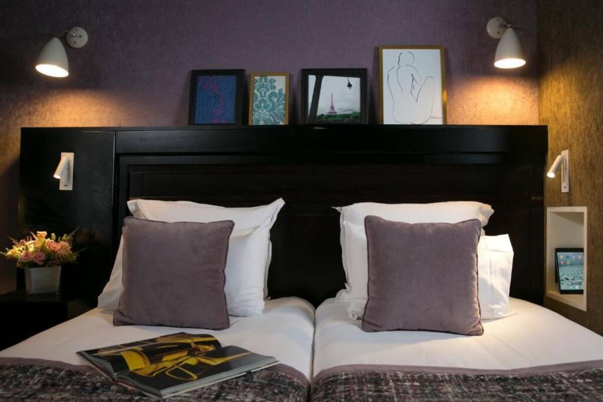 A double bed with two pillows, a bedside table with a lamp, and a small plant.