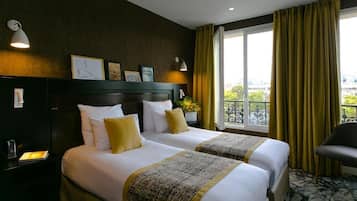 A hotel room with two beds, a nightstand, a chair, a window with curtains, and a balcony view.