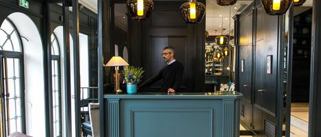 A reception area with a counter, a lamp, and a plant.