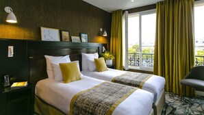 A hotel room with two beds, a nightstand, a chair, a window with curtains, and wall-mounted lights. - Hôtel de Neuville (Paris)