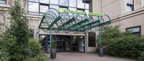 The entrance to Wyndham Garden hotel with a green metal archway and a sign above the door.