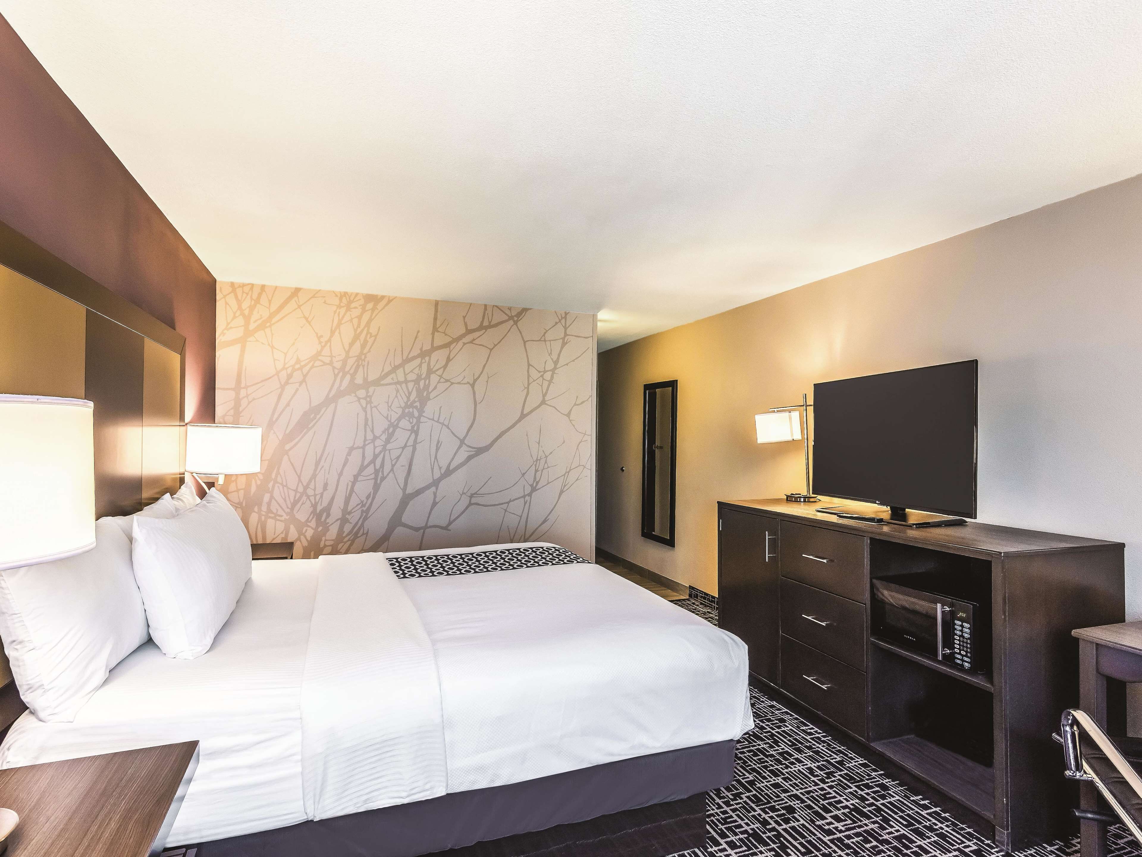 Una habitación de hotel con cama, televisión, escritorio y cómoda.