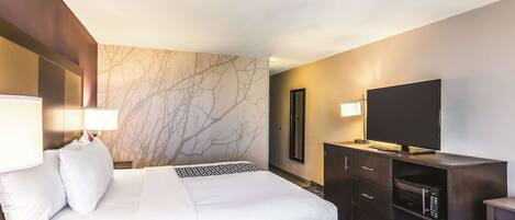 A hotel room with a bed, a TV, a desk, and a dresser.