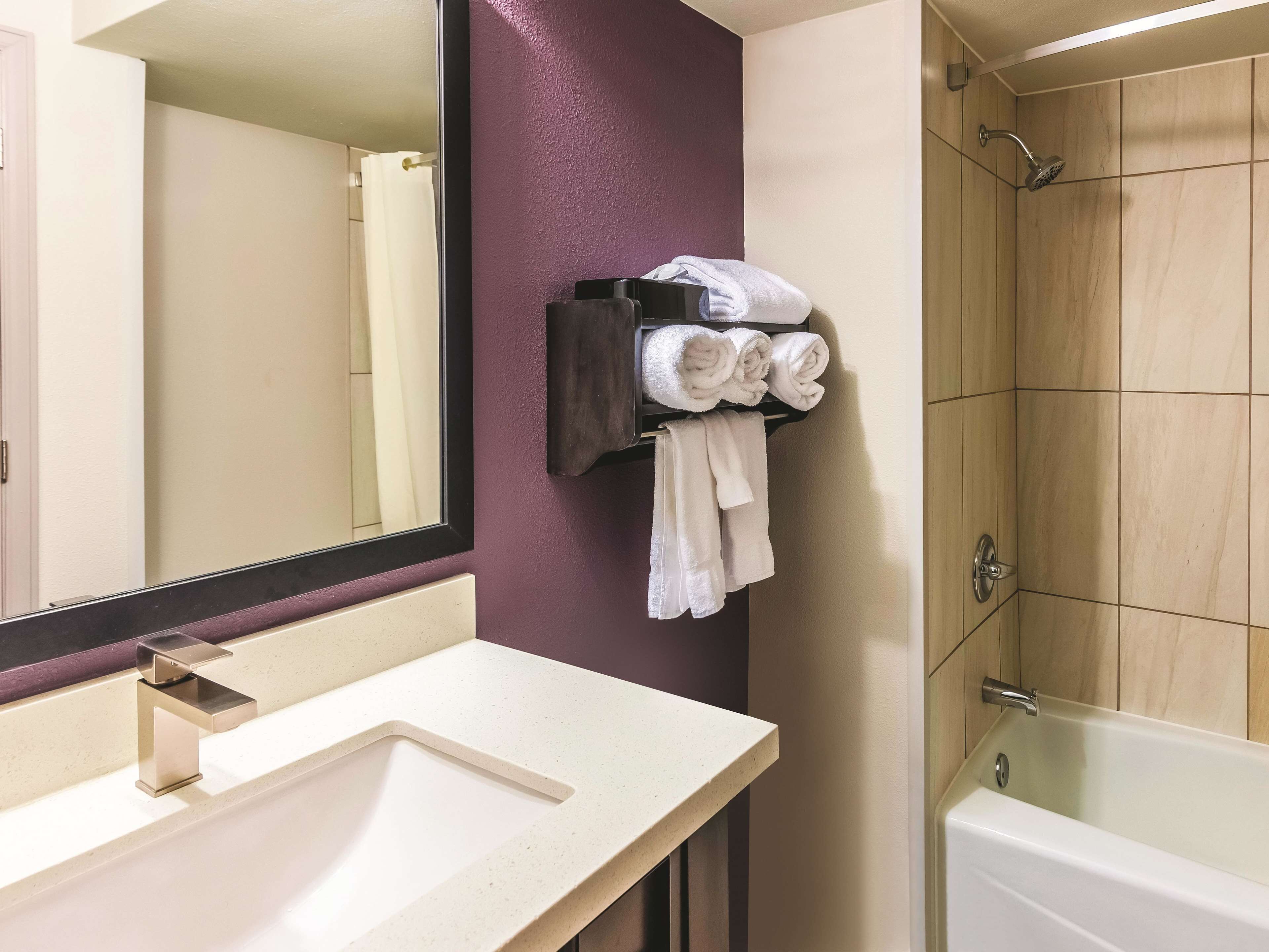 A bathroom with a sink, mirror, towel rack, and a bathtub.